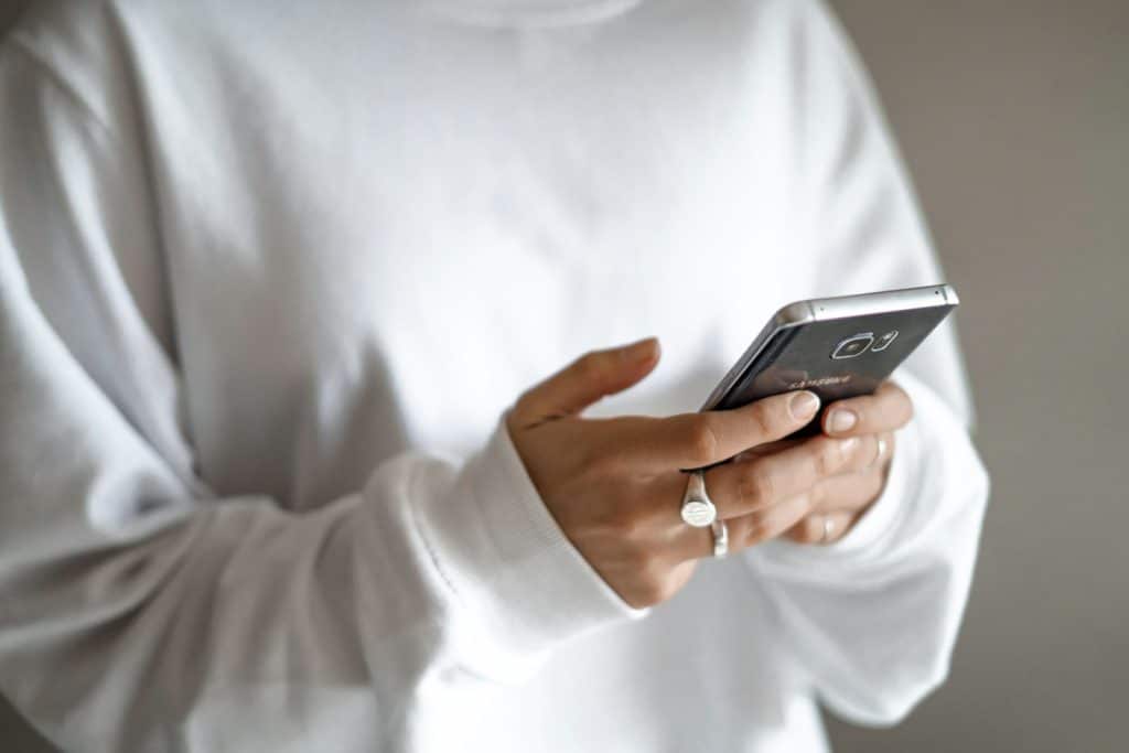 osoba u belom duksu gleda polovan mobilni telefon