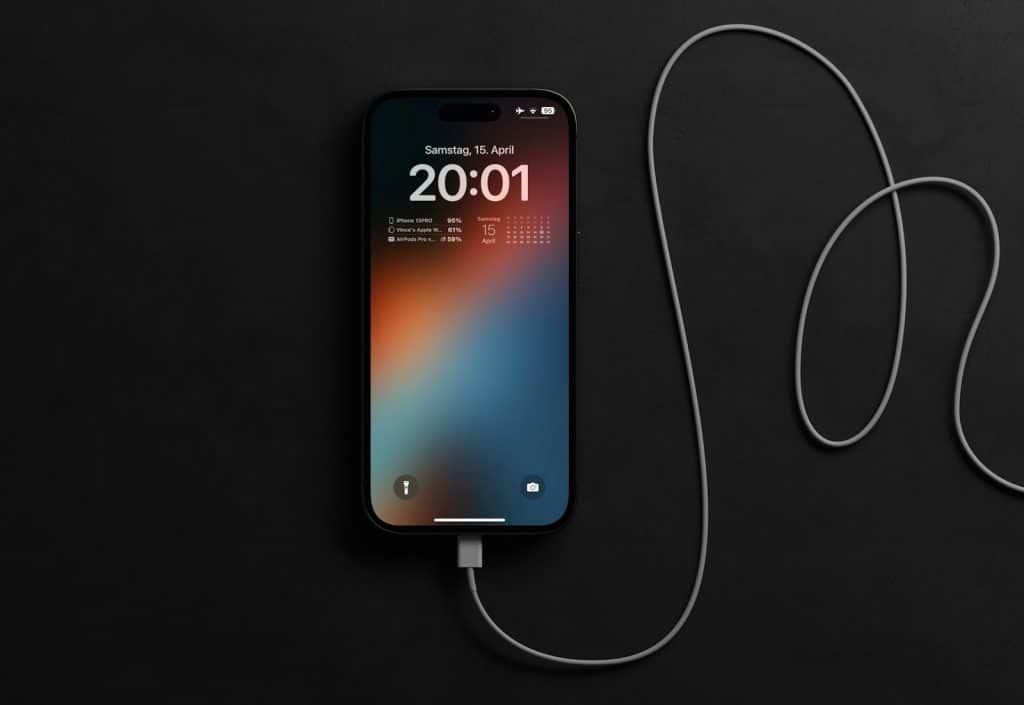 Pametni telefon povezan na punjač, sa ekranom koji prikazuje da je baterija telefona pri kraju i da je potrebno punjenje.