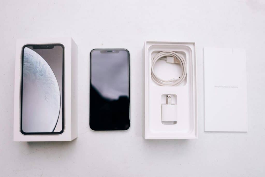 A neatly arranged flatlay of a smartphone with its packaging and accessories on a white background.