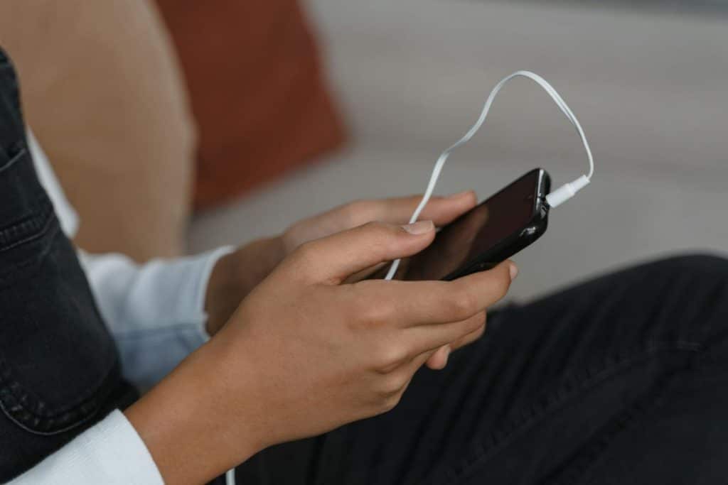 A person holds a smartphone with earbuds connected, capturing modern technology engagement.