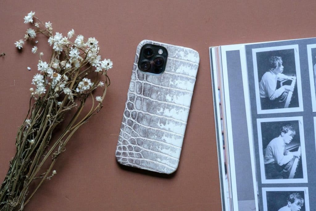 Luxury smartphone with leather case and white flowers for a modern aesthetic.