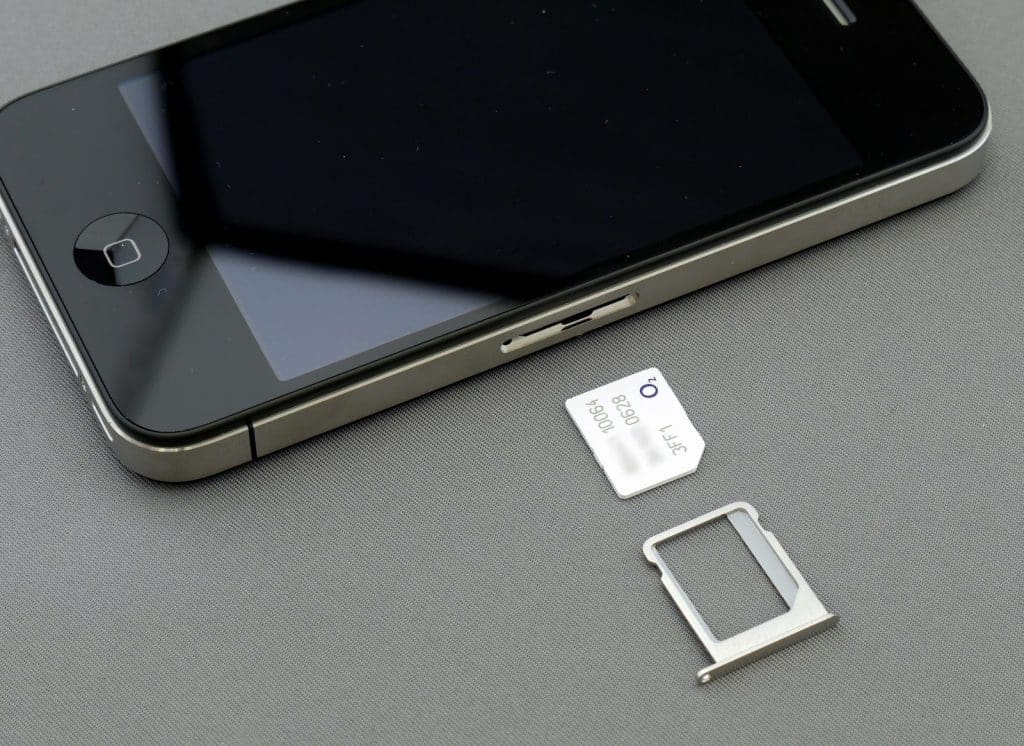 Telefon sa izvađenim slotom i SIM karticom pored njega – prikaz kako SIM kartica za telefon izgleda i koristi se u uređaju.