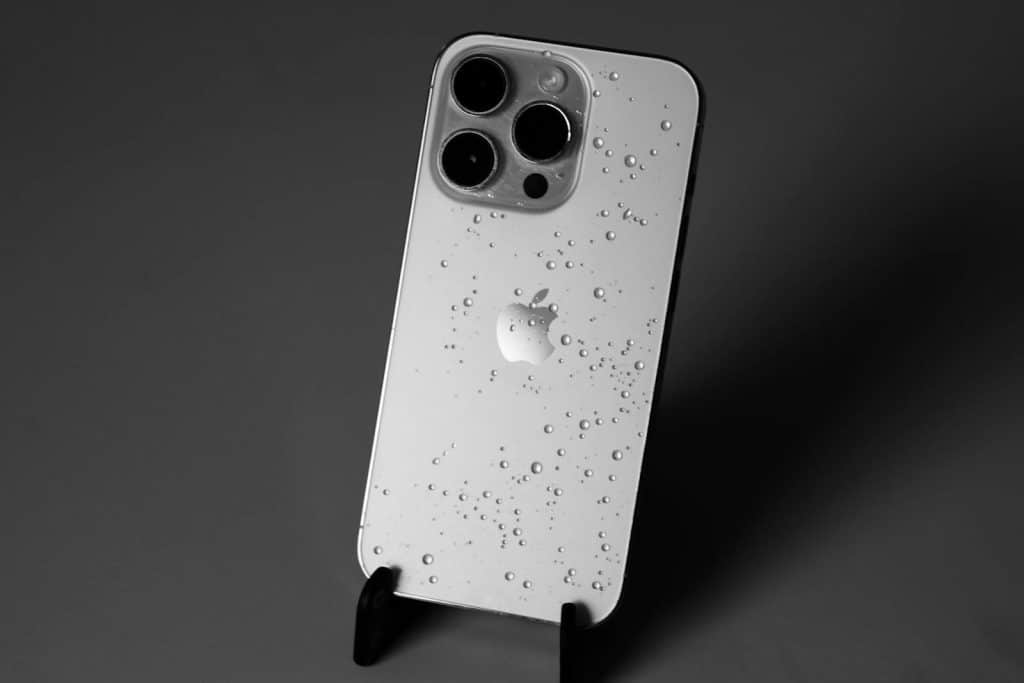 Pametni telefon sa kapljicama vode na kućištu, prikaz problema kada je telefon upao u vodu i potrebna je brza reakcija i servis.