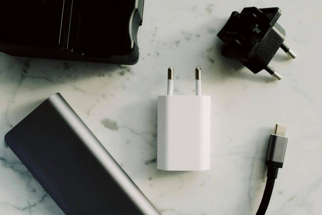 Beli adapter za punjenje mobilnog telefona na stolu, primer opreme koja može predstavljati neispravan punjac i izazvati probleme sa baterijom.