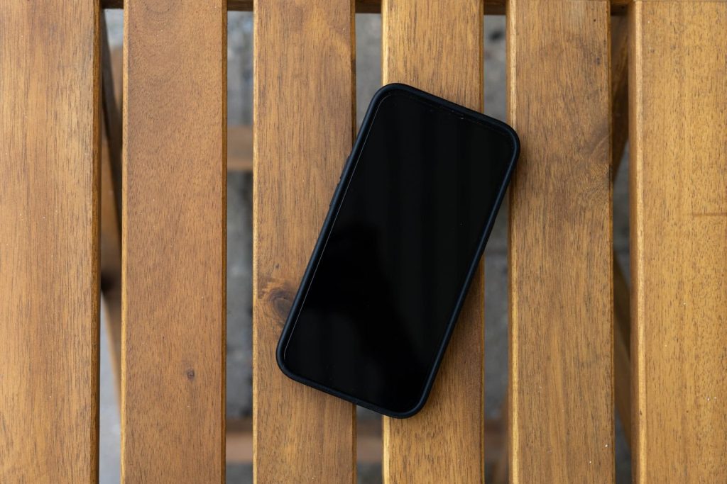 Telefon sa crnim ekranom na drvenom stolu